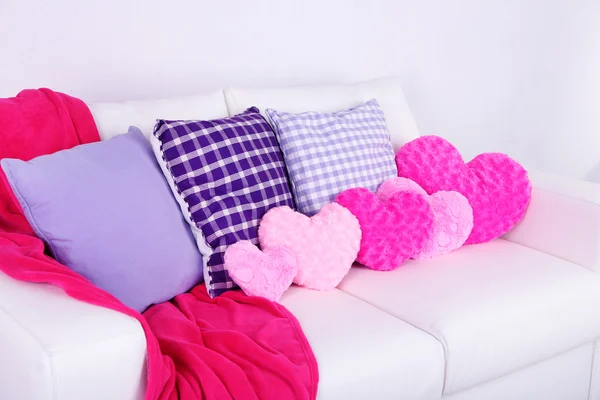 Almofadas em forma de coração rosa, xadrez no sofá branco — Fotografia de Stock