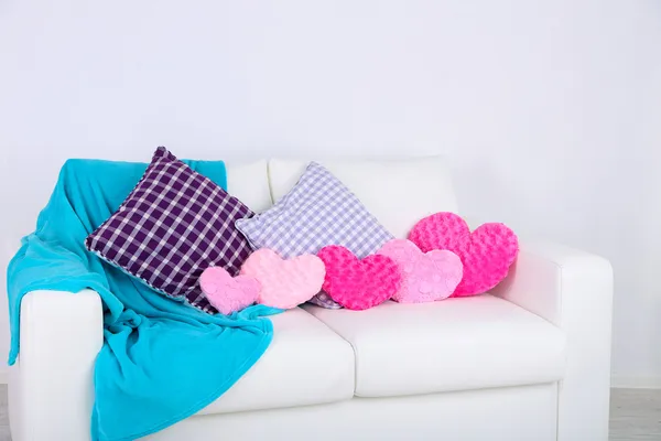 Pink heart shaped pillows, plaid on white sofa — Stock Photo, Image