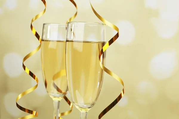 Glasses of champagne with serpentine on light background — Stock Photo, Image