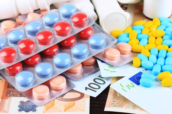 Medicamentos prescritos no fundo do dinheiro que representam custos crescentes de cuidados de saúde. Em fundo de madeira — Fotografia de Stock