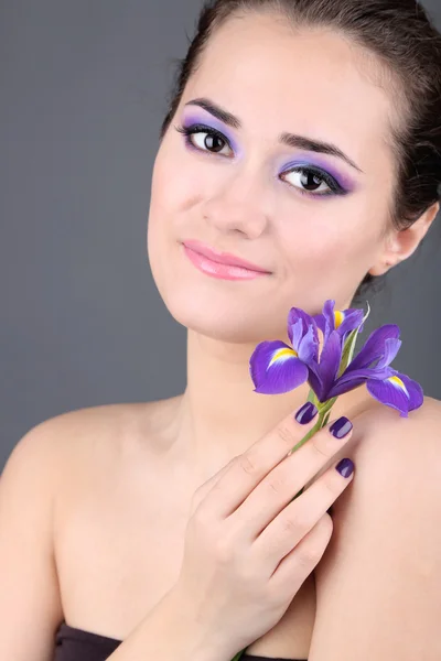 Hermosa mujer joven con flor sobre fondo gris — Foto de Stock