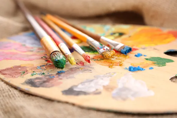 Composition with brushes on used wooden palette, on wooden background — Stock Photo, Image