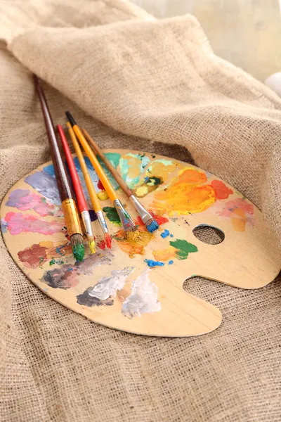 Composition with brushes on used wooden palette, on wooden background — Stock Photo, Image
