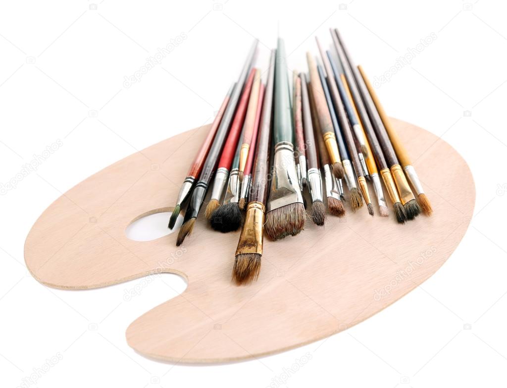 Many brushes on wooden palette, isolated on white