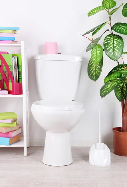 WC bianco ciotola e stand con libri, su sfondo parete a colori — Foto Stock