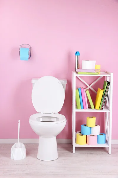 White toilet bowl and stand with books, on color wall background — Stock Photo, Image