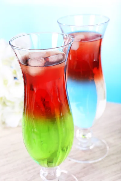 Glasses of cocktails on table on light blue background — Stock Photo, Image