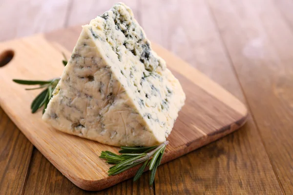 Smakelijke blauwe kaas met rozemarijn, op houten tafel — Stockfoto