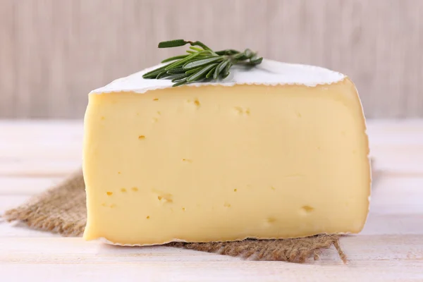 Tasty Camembert cheese with rosemary, on wooden table — Stock Photo, Image