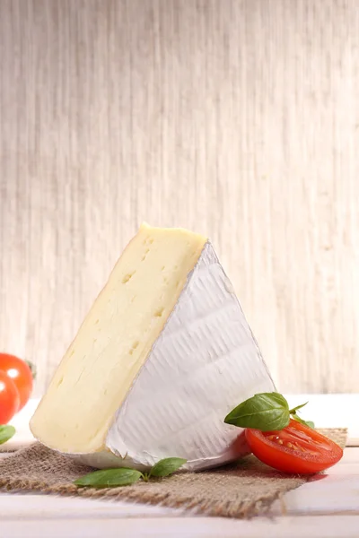 Queijo saboroso Camembert com manjericão e tomate, sobre mesa de madeira — Fotografia de Stock