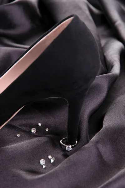 Hermoso anillo en el talón de zapato femenino negro, sobre fondo de seda — Foto de Stock