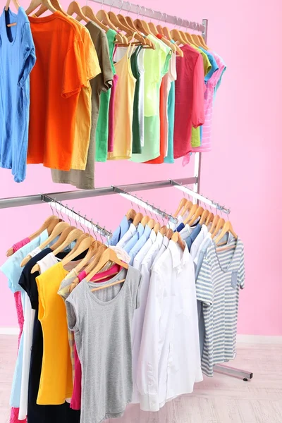 Různé šaty na ramínka, na růžovém pozadí — Stock fotografie