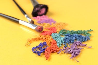 ezilmiş göz farı ve Sarı zemin üzerine profesyonel makyaj fırçası