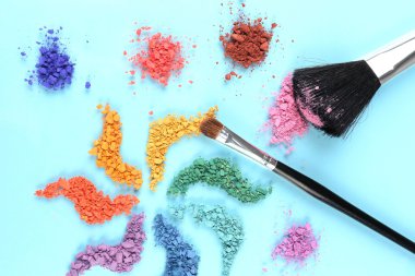 Gökkuşağı göz farı ve profesyonel makyaj fırçası mavi zemin üzerine ezilmiş