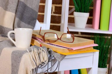 Composition with glasses and books, on chair, on cabinet and wall background clipart