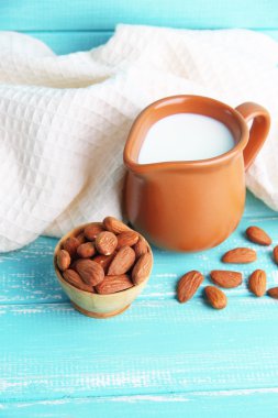 badem sütü kabı içinde kase renkli ahşap zemin üzerinde bademli