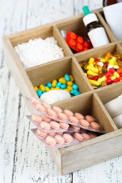 Medical pills, ampules in wooden box, on color background — Stock Photo, Image