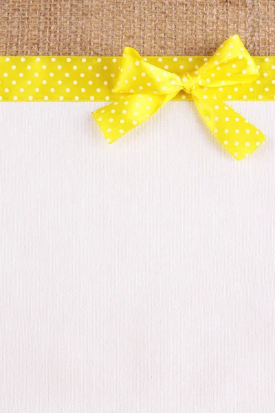 Sackcloth with color ribbon and bow on color fabric background — Stock Photo, Image