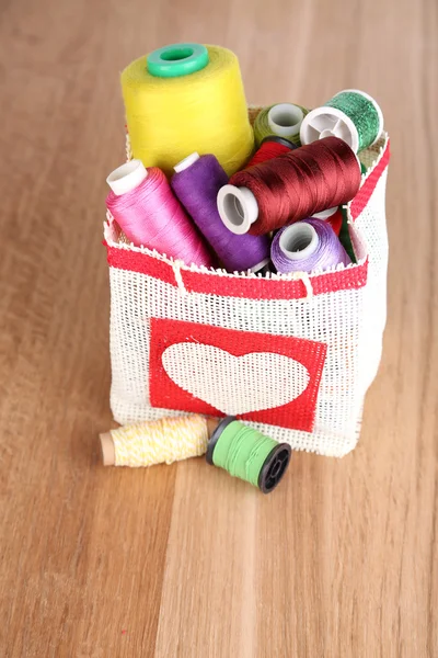 Colorful bobbins of thread  in bag, on wooden background — Stock Photo, Image