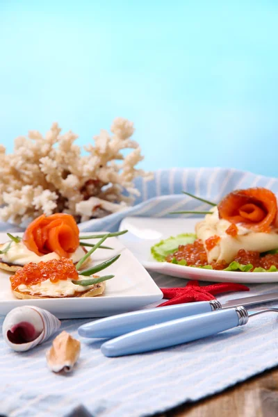 Panqueques con caviar rojo, salmón y mayonesa, cebolla verde, sobre plato, sobre servilleta de color, sobre mesa de madera, sobre fondo brillante —  Fotos de Stock