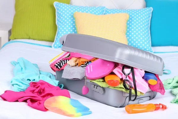 Grey suitcase with clothing on bed close-up — Stock Photo, Image