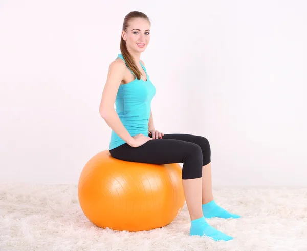 Jovem bela menina fitness exercitando com bola laranja no ginásio — Fotografia de Stock