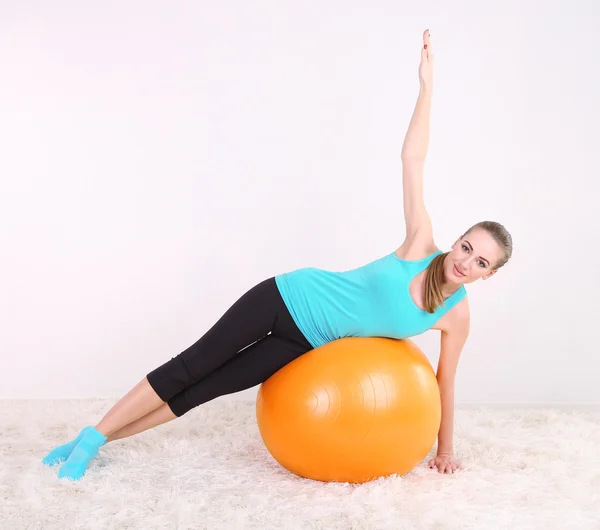 Young beautiful fitness girl exercising with orange ball in gym — Stock Photo, Image