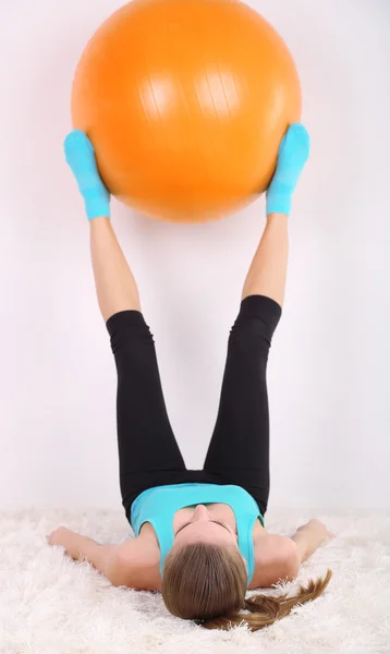 Giovane bella ragazza fitness che si esercita con la palla arancione in palestra — Foto Stock