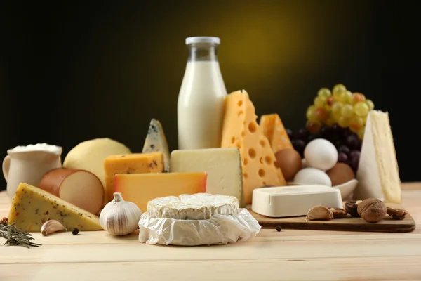 Tasty dairy products on wooden table, on dark background — Stock Photo, Image