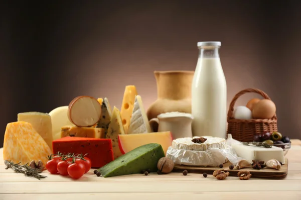 Tasty dairy products on wooden table, on dark background — Stock Photo, Image