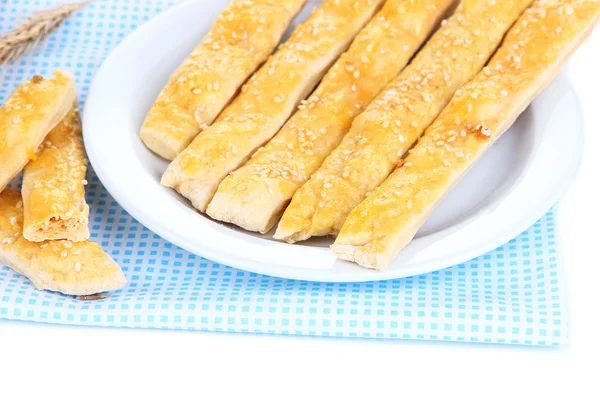 Gustosi bastoncini di pane su piatto su tovagliolo di colore, isolati su bianco — Foto Stock