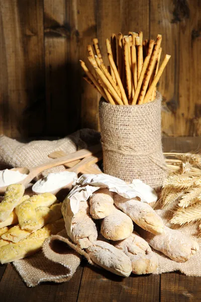 Palitos de pan sobre tela de saco sobre fondo de madera — Foto de Stock