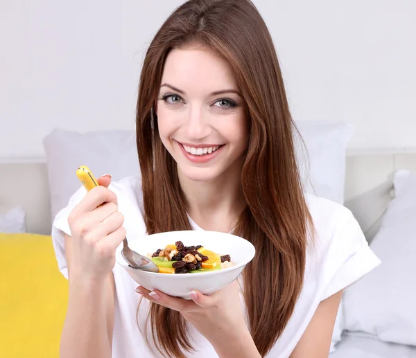 Young beautiful woman on bed with fruit salad — Zdjęcie stockowe