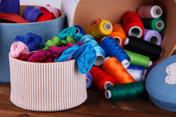 Decorative boxes with colorful skeins of thread and zippers on table close up — Stock Photo, Image