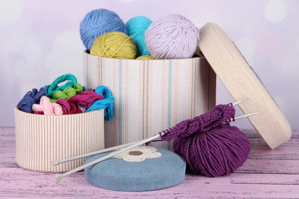 Decorative boxes with colorful skeins of thread on table on bright background — Stock Photo, Image