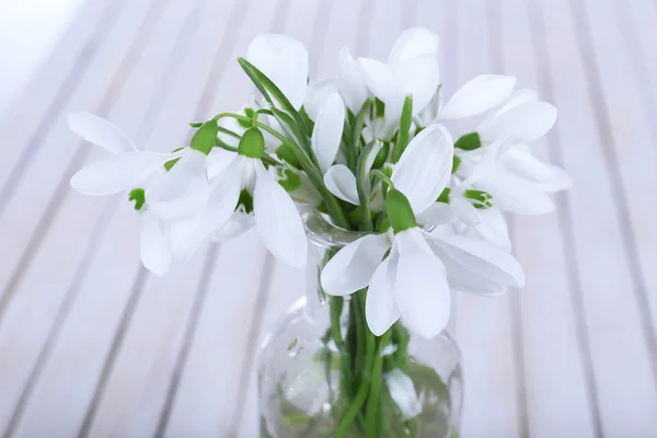 Krásná kytice sněženky v vázy na dřevěné pozadí — Stock fotografie