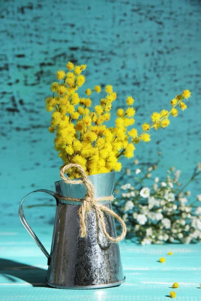 A mimosa virágok vázában a kék fából készült asztal gallyak — Stock Fotó