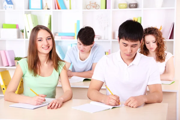 Grupo de jovens estudantes sentados em sala de aula — Fotografia de Stock