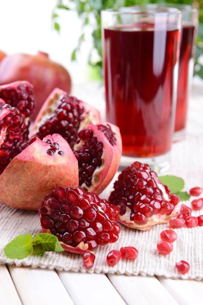 Ripe pomegranates with juice on table on light background — Stock Photo, Image