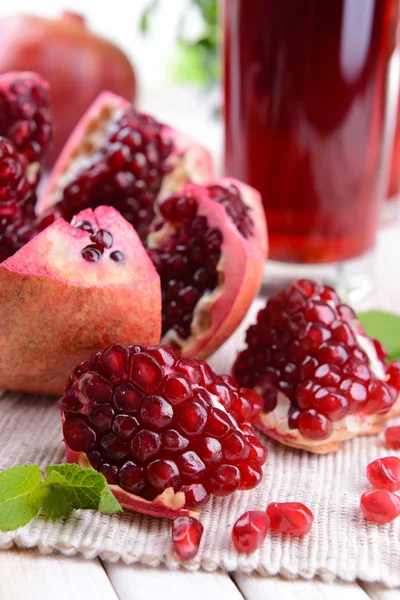 Rijp granaatappels met SAP op tafel op lichte achtergrond — Stockfoto