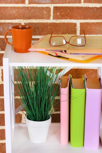 Composição com óculos e livros, no armário, no fundo da parede de cor — Fotografia de Stock