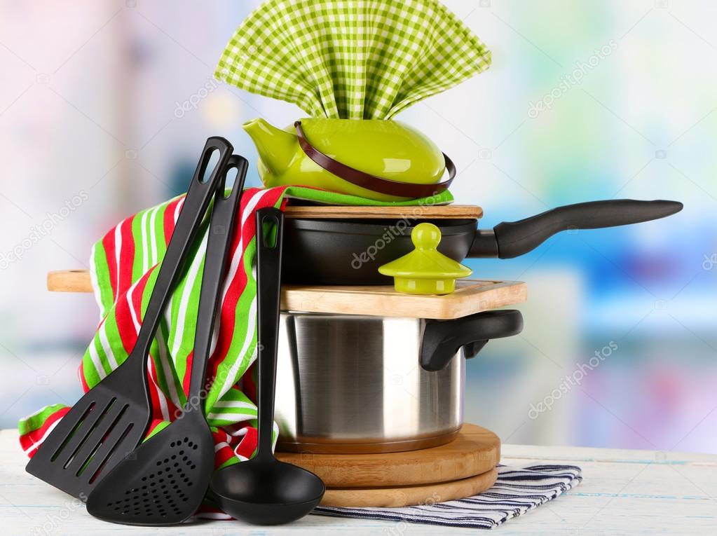 Stacked cooking equipment on wooden table, on light background