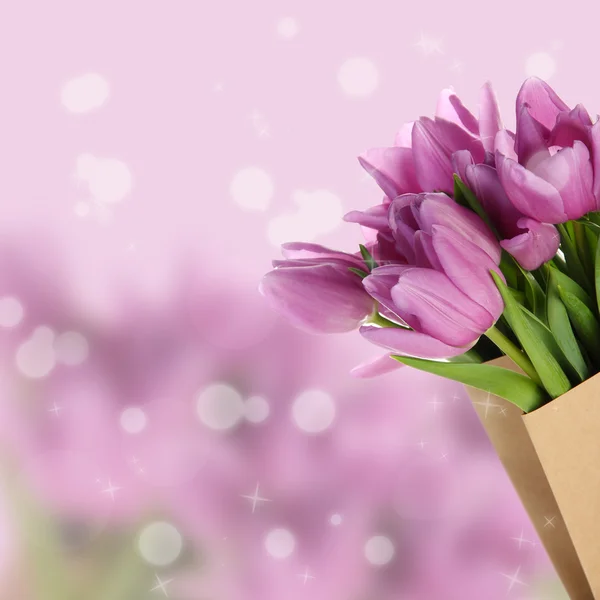Piękny bukiet tulipanów fioletowy w papierowej torebce na jasnym tle — Zdjęcie stockowe