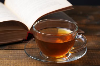 ahşap zemin üzerinde kitapla sıcak çay