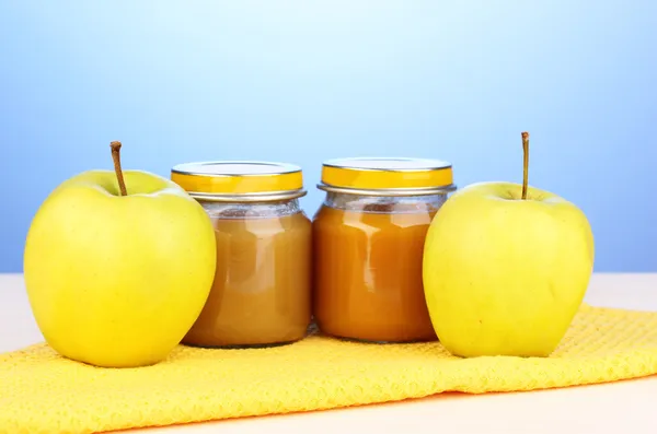 Jars of baby puree on napkin on blue background — Stock Photo, Image