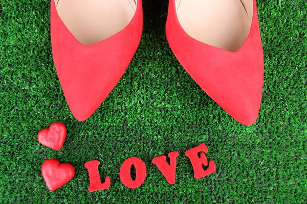 Sapatos femininos vermelhos bonitos, no fundo de grama verde — Fotografia de Stock
