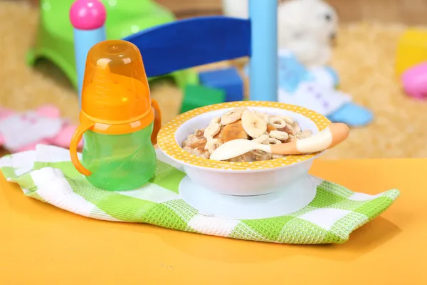 Чаша каши для малыша и игрушки на столе, на фоне игрушек — стоковое фото