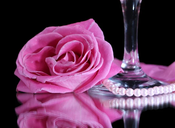Состав с розовым игристым вином в стакане и розы изолированы на черном — стоковое фото