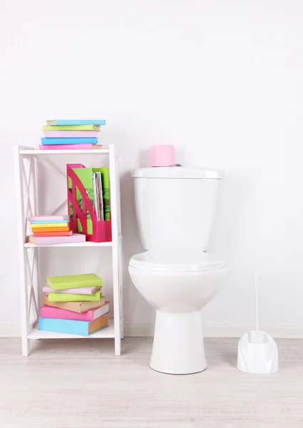 Bílé záchodové mísy a stánek s knihami, na zeď na barvu pozadí — Stock fotografie