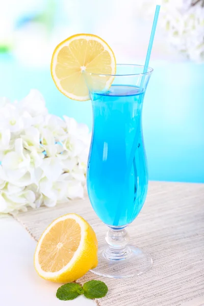 Glass of cocktail on table on light blue background — Stock Photo, Image